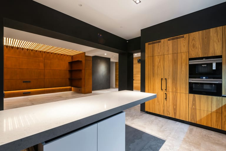 Cuisine sur mesure moderne avec îlot central blanc, façades bois noyer et plan de travail clair
